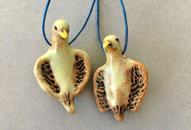 Two ceramic birds hanging on a string. This is the work of artist Elaine Parks