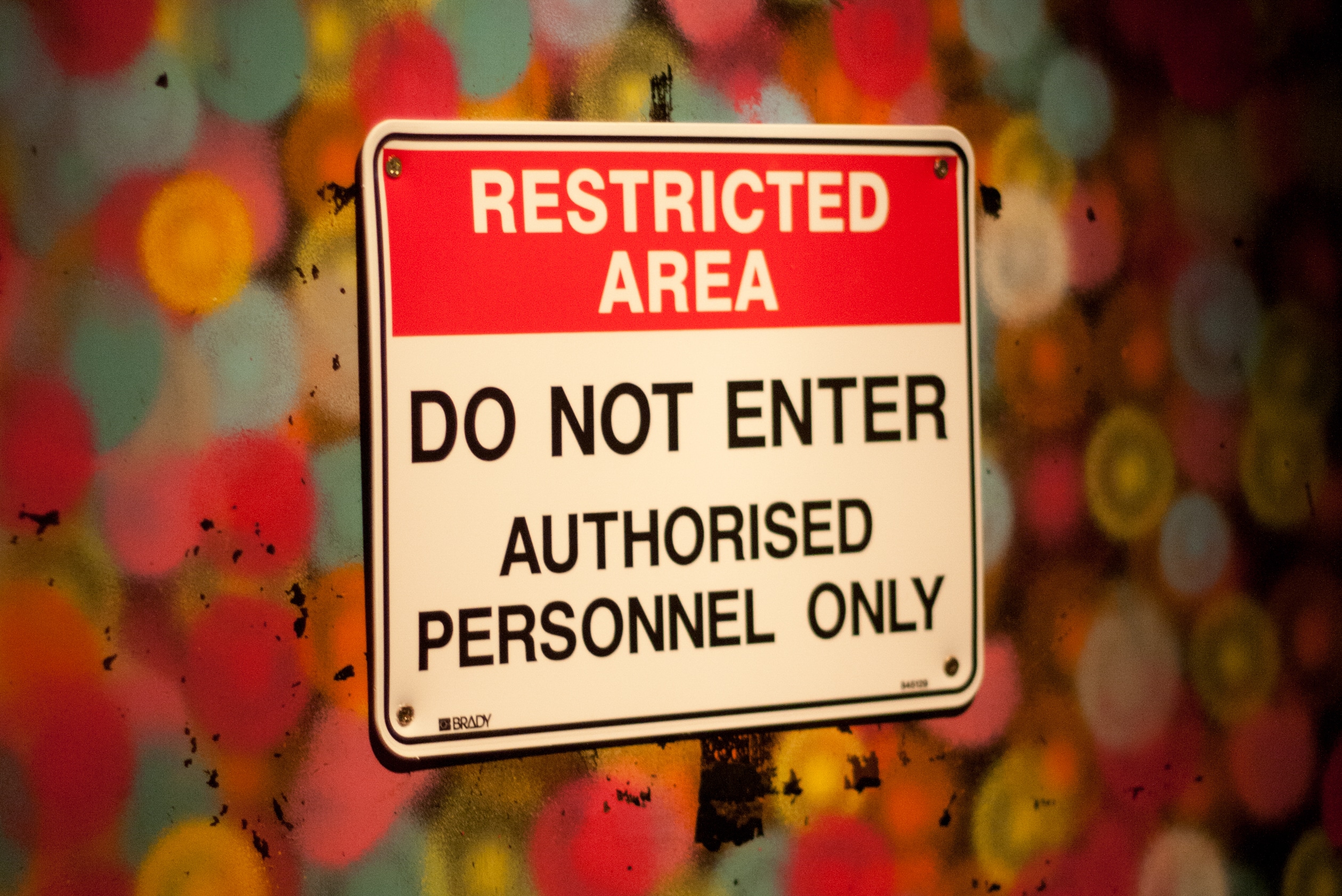 A photograph of a colorful background with a sign that reads Restricted Area Do Not Enter Authorised Personnel Only