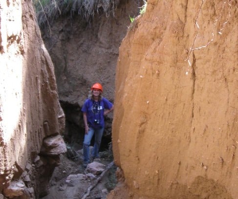 A photograph of a volunteer in a canyon cleaning up trash and debris