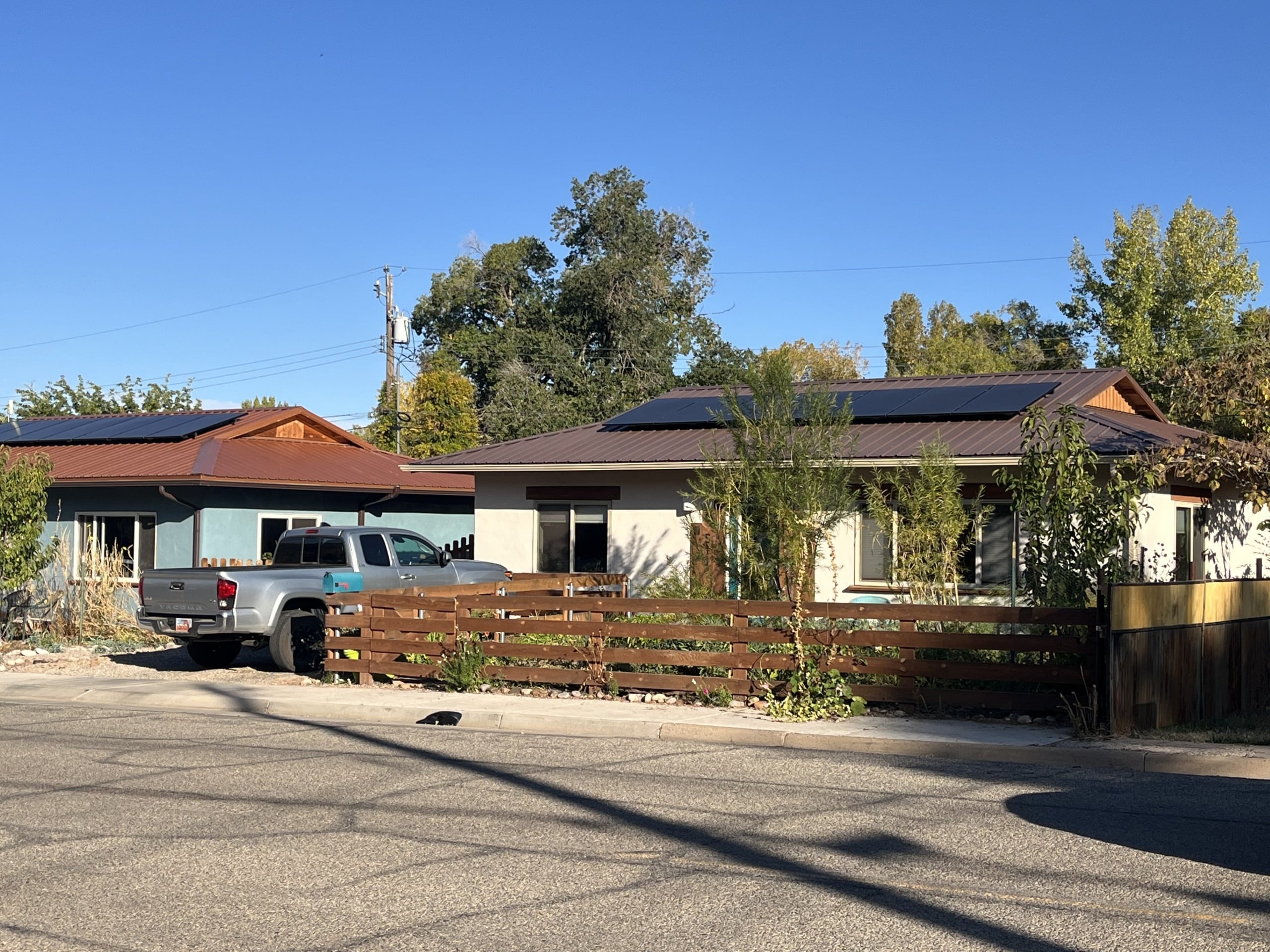 A photo of a home, with a wooden fence and a truck parked in the driveway