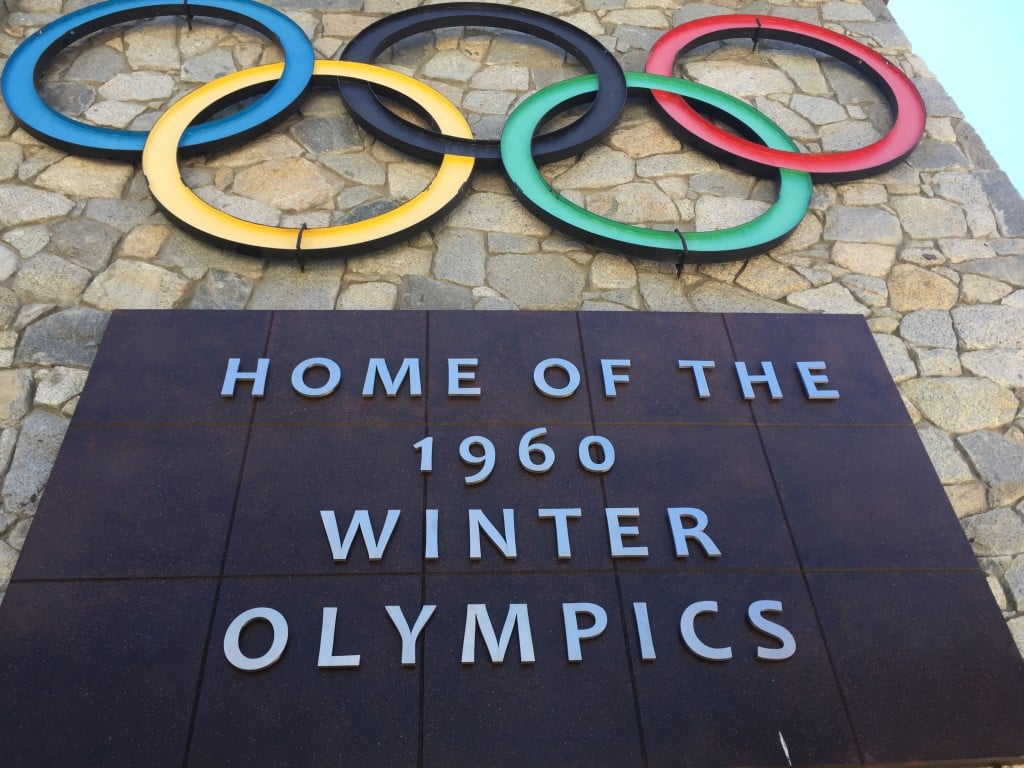 A photograph of the Olympics logo, with five rings, above a large plaque that reads "Home of the 1960 Winter Olympics"