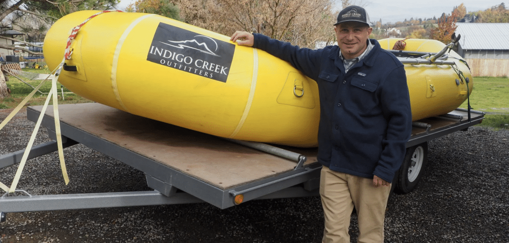 A photo of a man standing next to a large, yellow inflatable raft