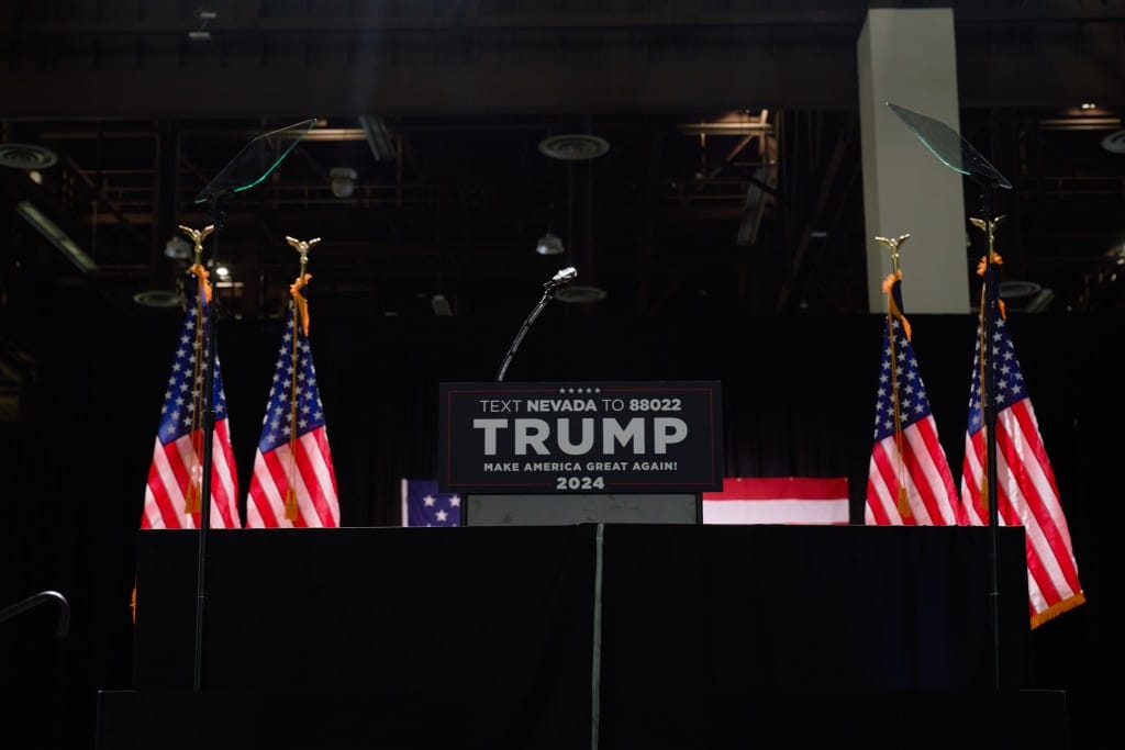 A photo of a podium with text that reads "Text Nevada to 88022, Trump, Make America Great Again! 2024." It's dark and there is no one there yet.