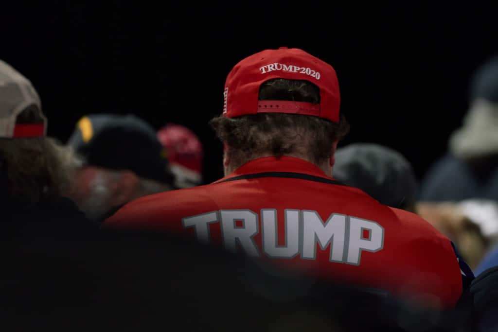 A photo showing a man wearing a red Trump 2020 hat and a red Trump shirt.