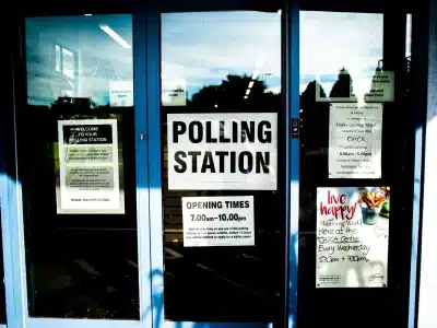 A photograph of a building with a sign on the front door that says "Polling Station"