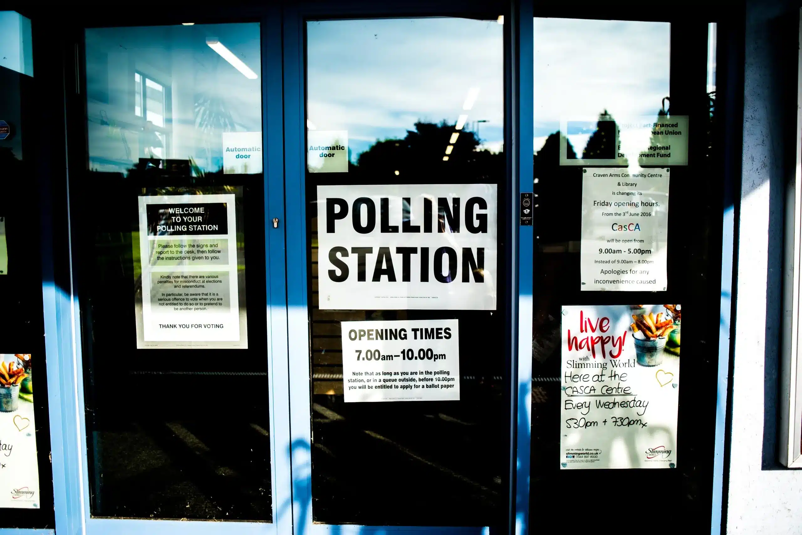 A photograph of a building with a sign on the front door that says "Polling Station"